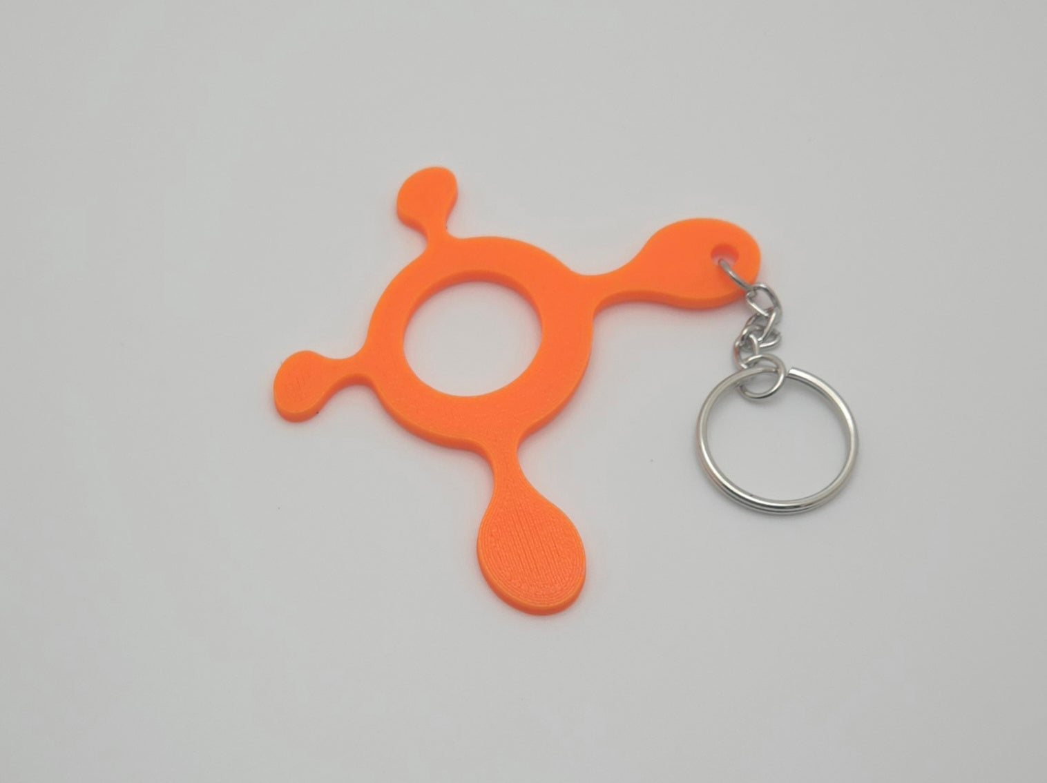 Orange fitness splat keychain, 3 inches wide, shown from a side angle