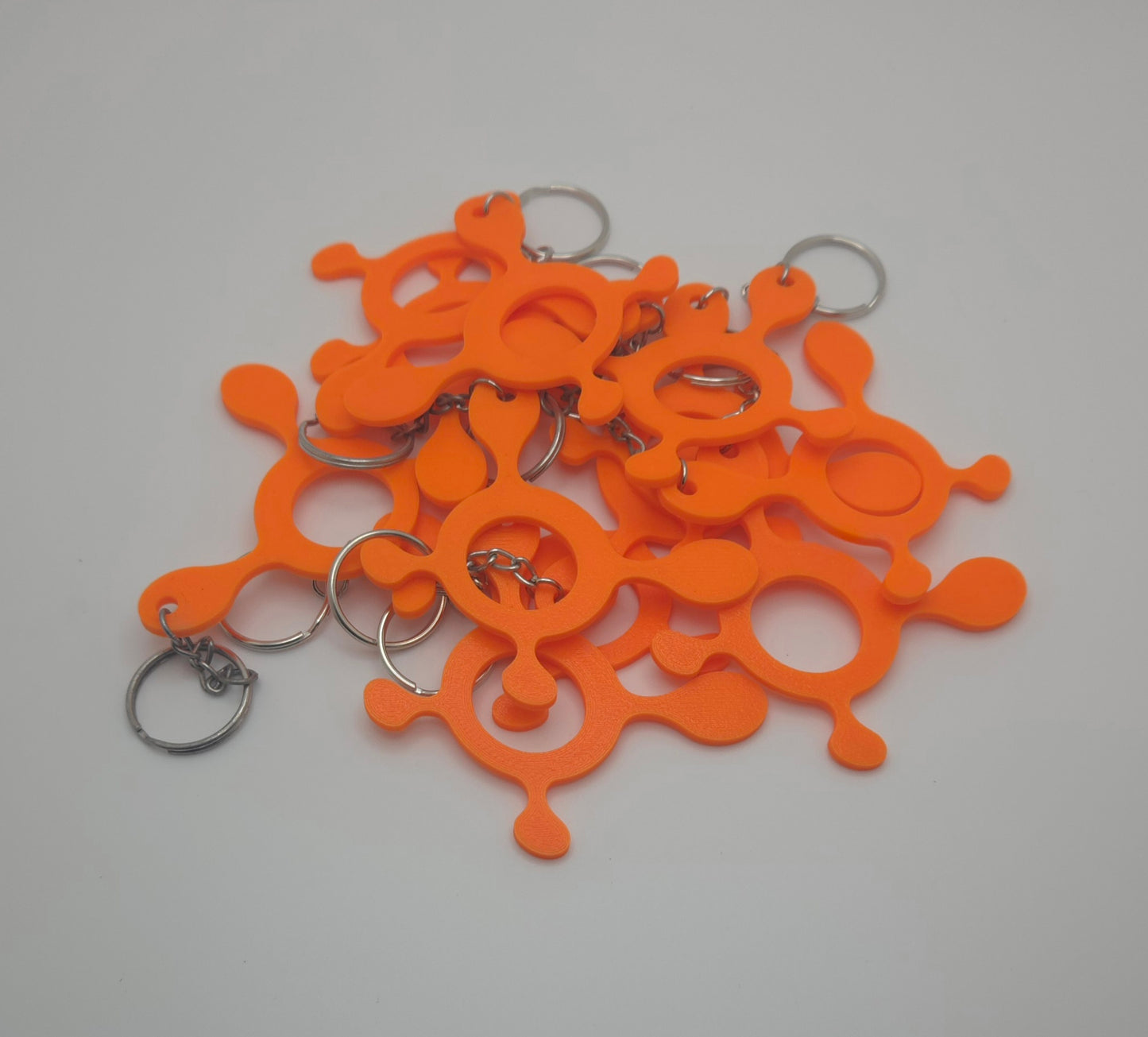 Multiple orange 3D printed splat keychains displayed together