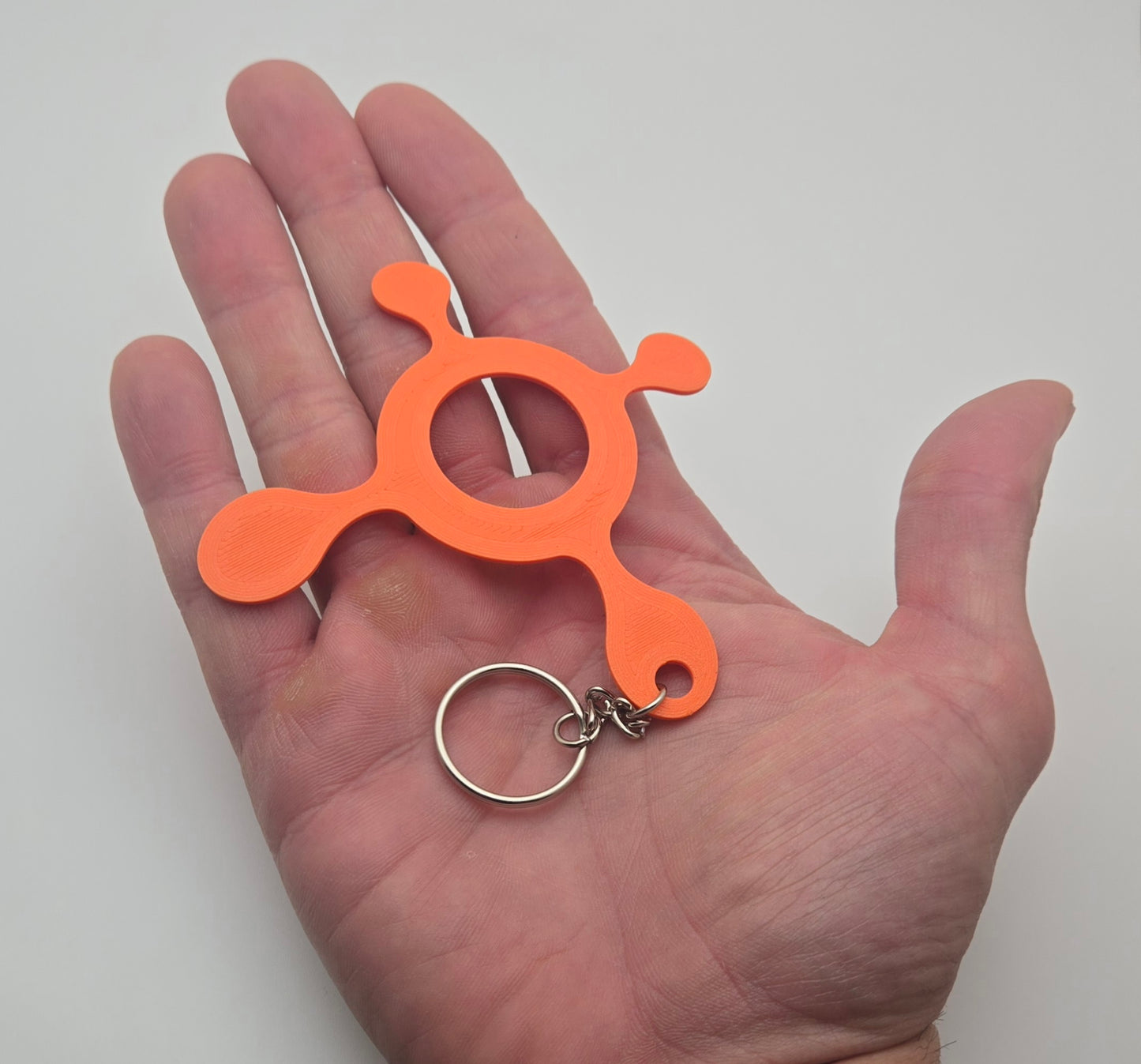 Orange splat keychain shown in hand to display size and detail